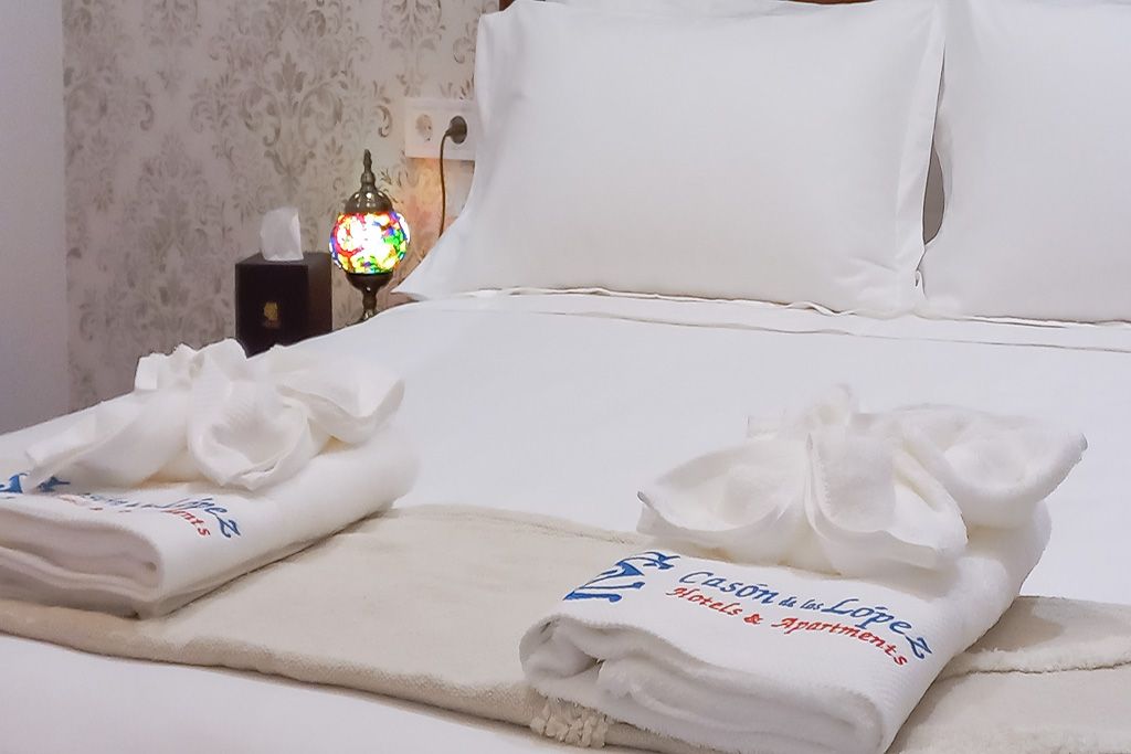 A bed with white sheets and pillows and towels on it