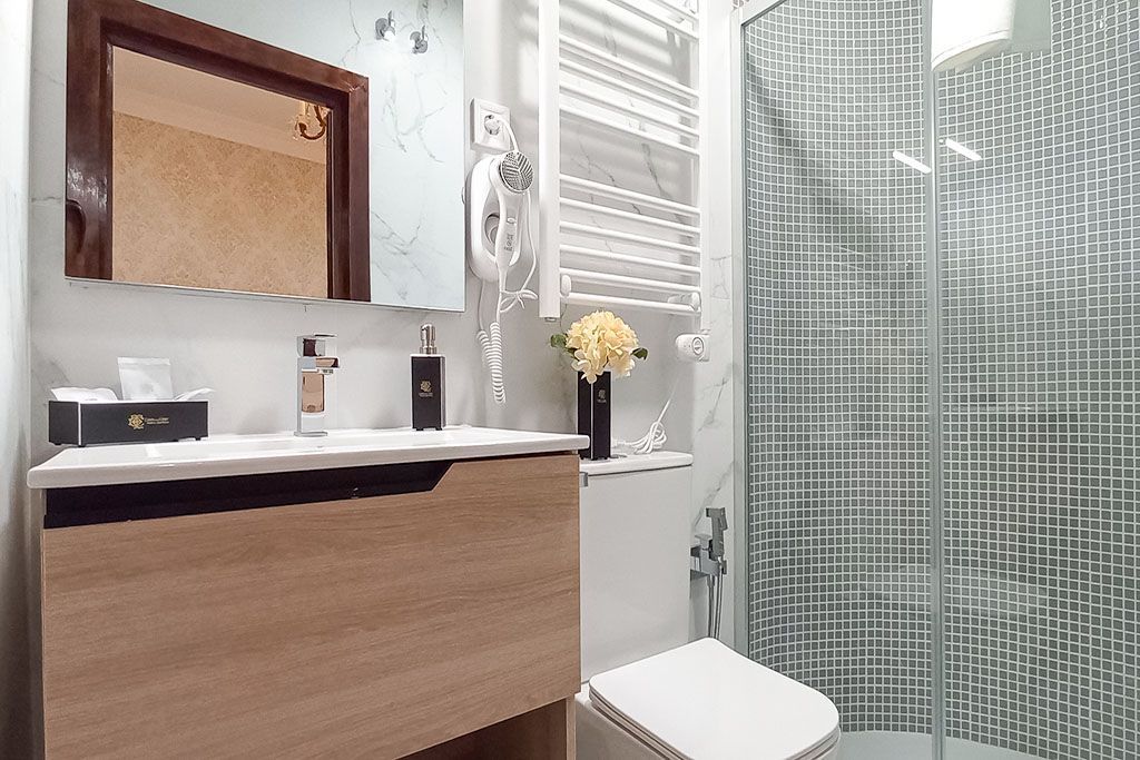 A bathroom with a toilet , sink , mirror and shower.