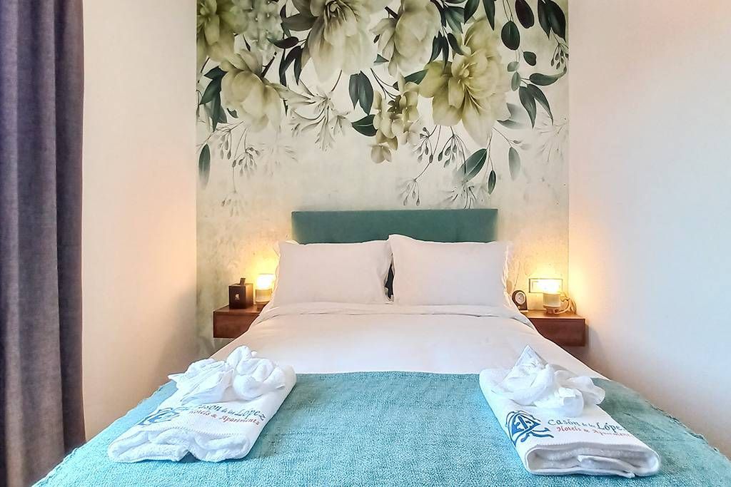 A bedroom with a bed and a floral wallpaper on the wall.