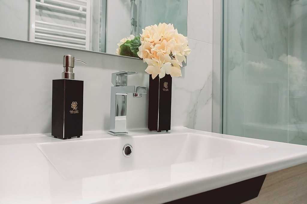 A bathroom sink with a vase of flowers on it.