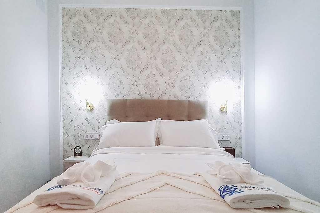 A bed with white sheets and pillows in a hotel room.