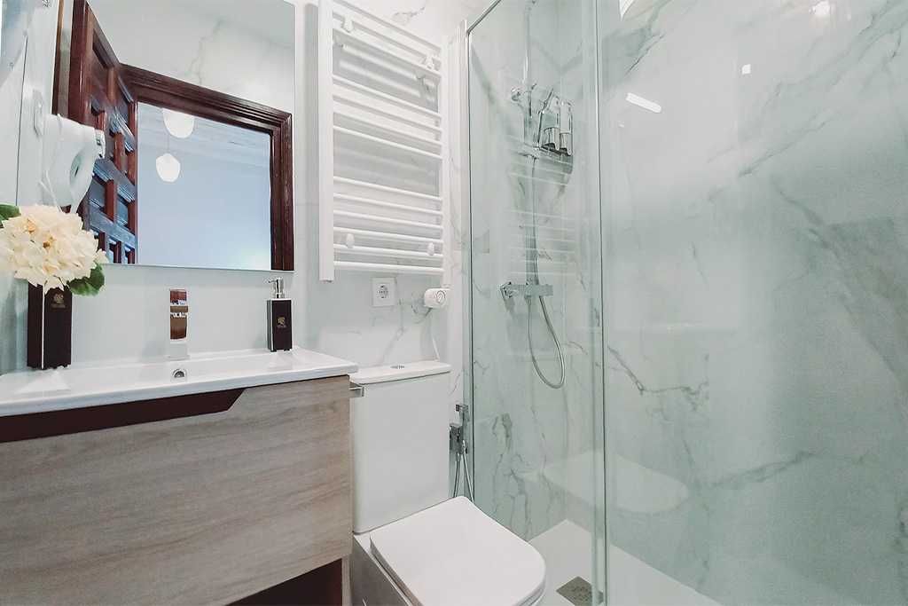 A bathroom with a toilet , sink , mirror and walk in shower.