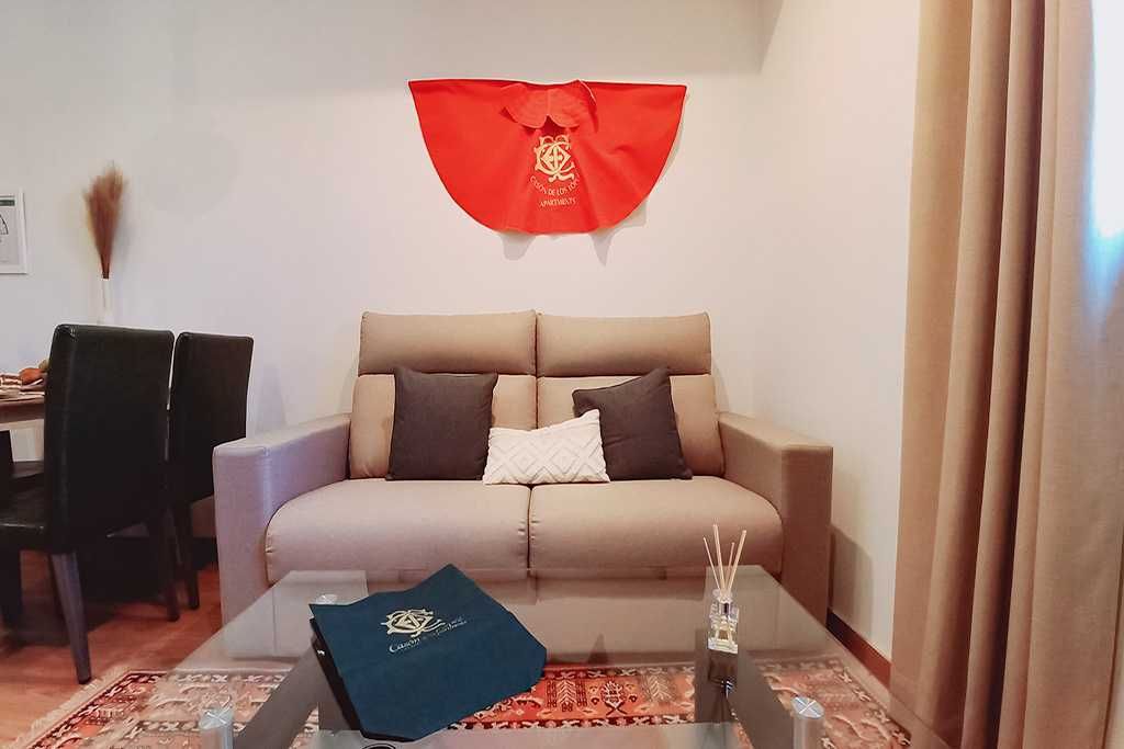 A living room with a couch and a red cape on the wall