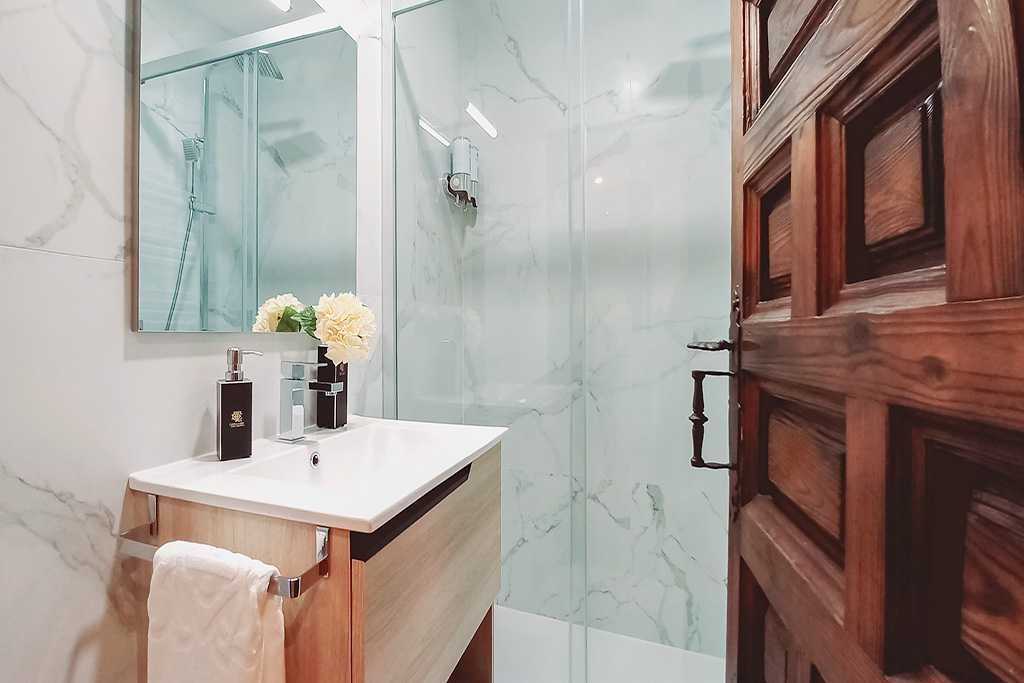 A bathroom with a sink , mirror and walk in shower.