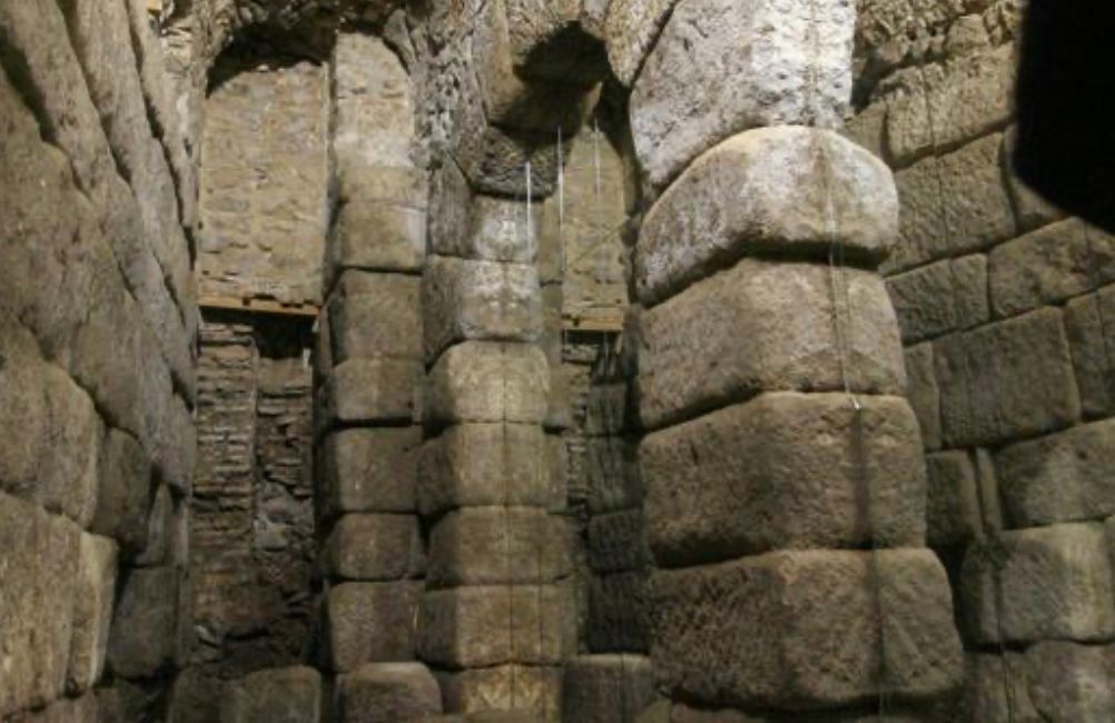 A very old stone building with columns and arches.