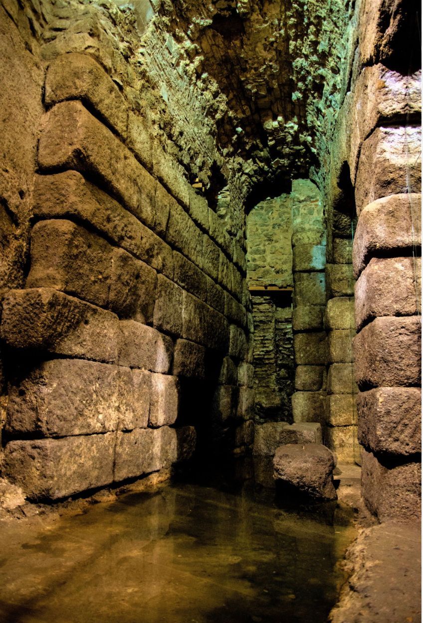 A very old building with a lot of bricks and water coming out of it.