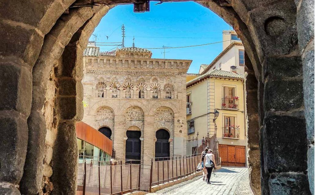A man is walking down a cobblestone street in front of a building.