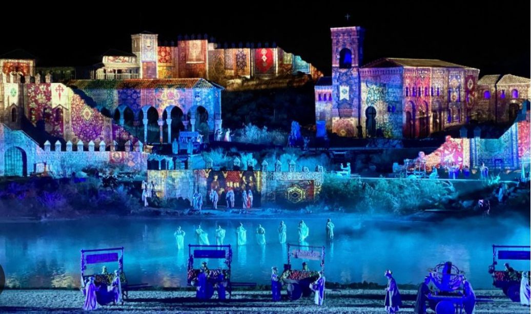 A group of people are standing in front of a building that is lit up at night.