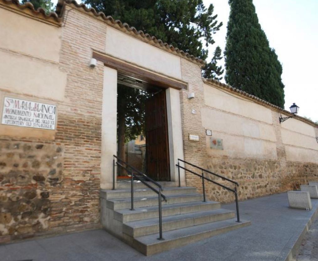 A stone wall with stairs leading up to a door with a sign on it that says 