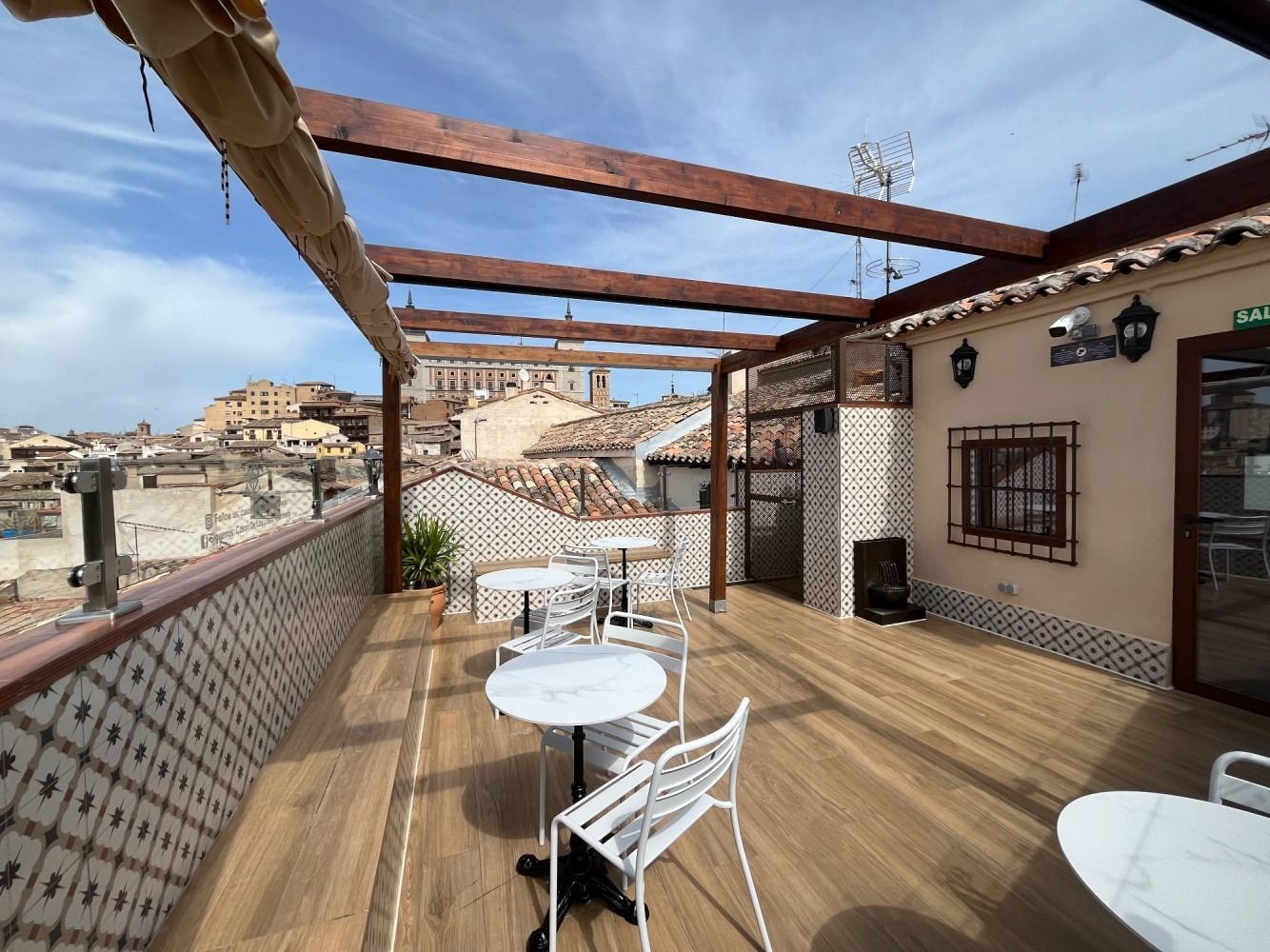 There are tables and chairs on the roof of a building.