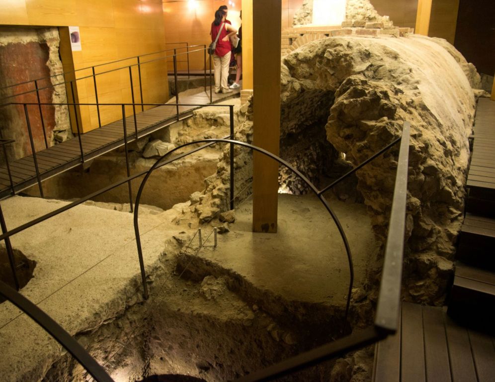 A group of people standing in a room with stairs and a fence