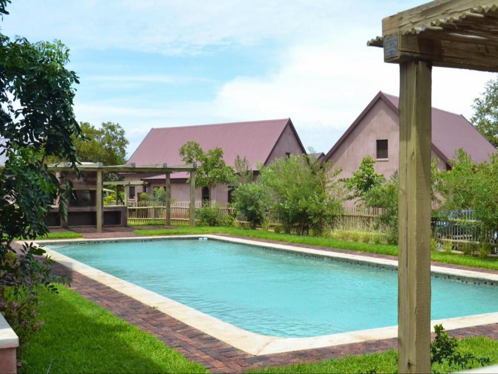 a large swimming pool in front of a house with a purple roof