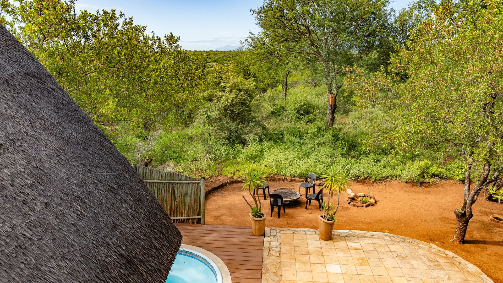 an aerial view of a patio with a thatched roof and a swimming pool