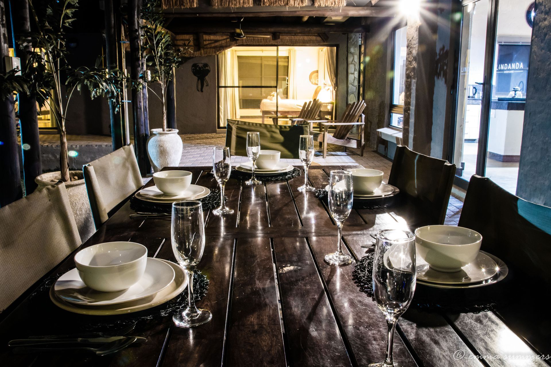 a long wooden table with plates , bowls and glasses on it .