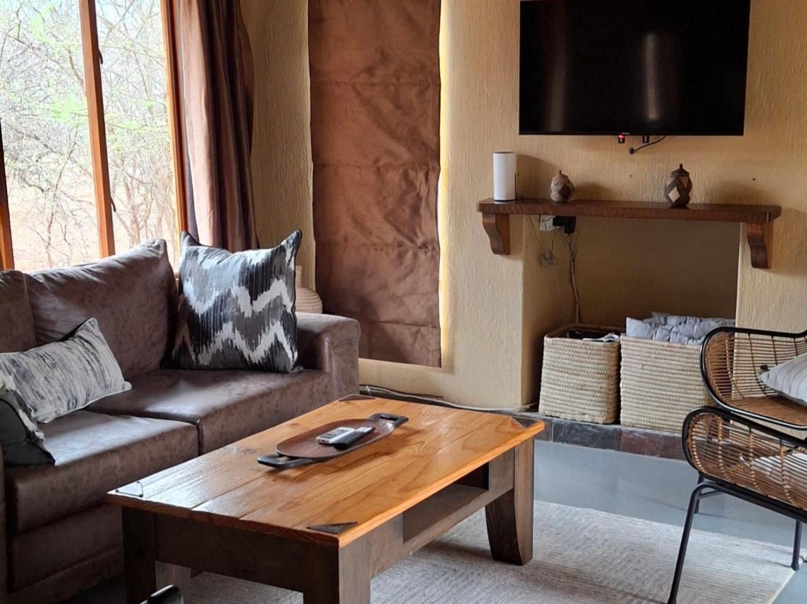 Living room with brown sofa, wooden coffee table, and television on the wall.