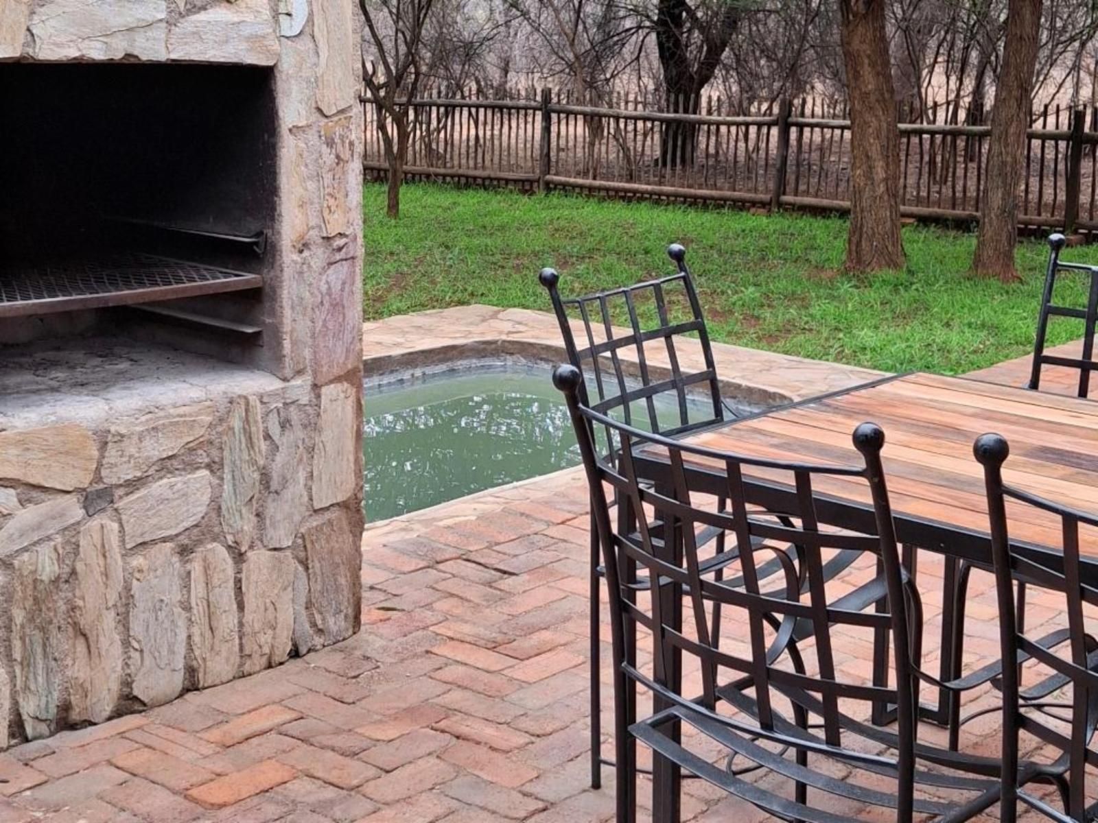 Outdoor dining area with a braai, small pool, and table with chairs.