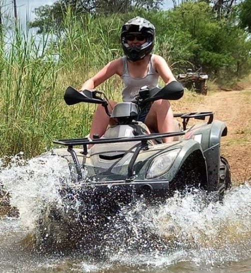 a woman is riding a four wheeler through the water .