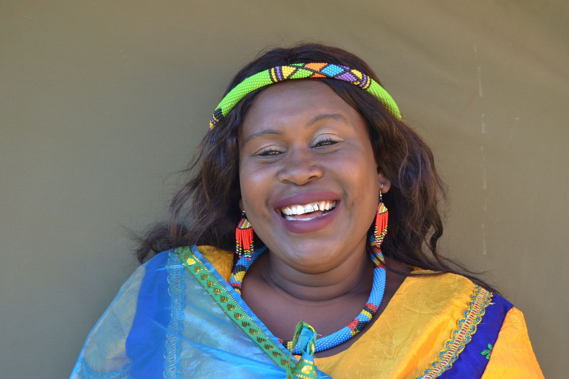 Smiling woman wearing colorful traditional jewelry and headpiece.