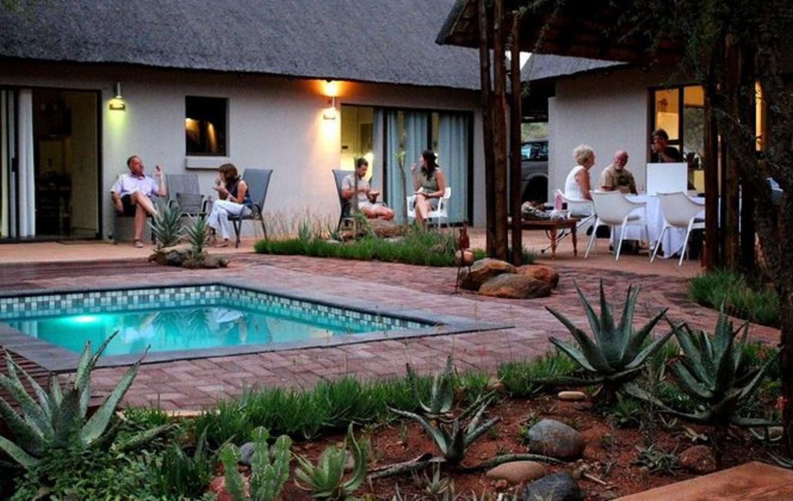 People relax by a pool at a resort, enjoying drinks.