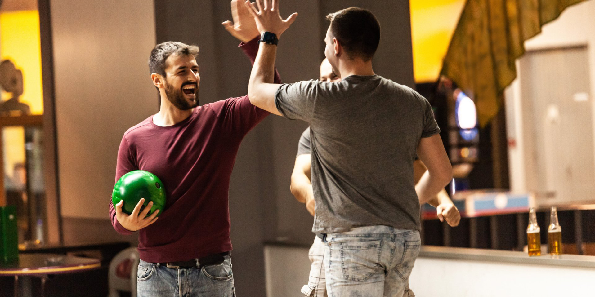 Two men are giving each other a high five while playing bowling.