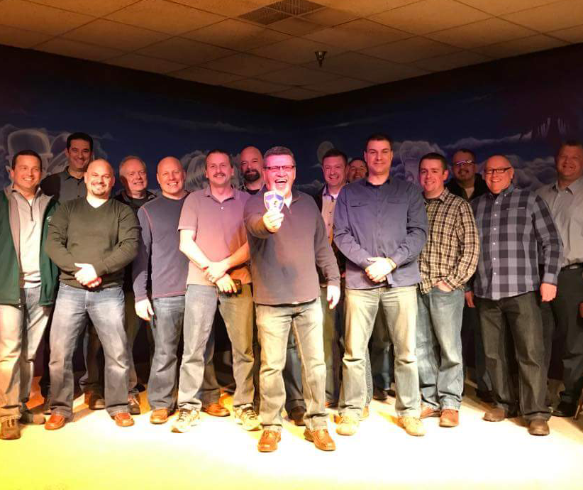 A group of men are posing for a picture and one man is giving a thumbs up