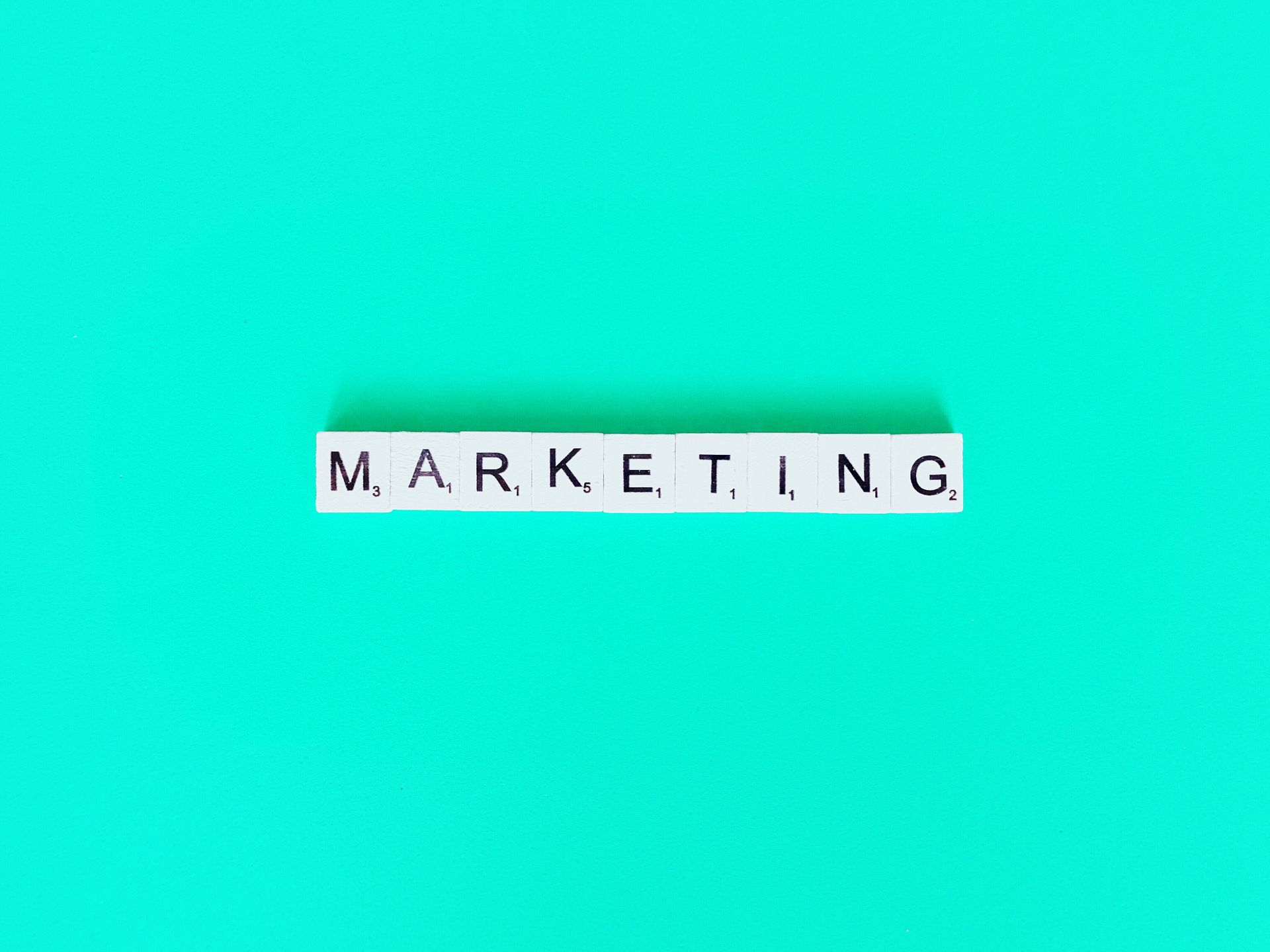 a palavra marketing está escrita em blocos de scrabble sobre um fundo verde.