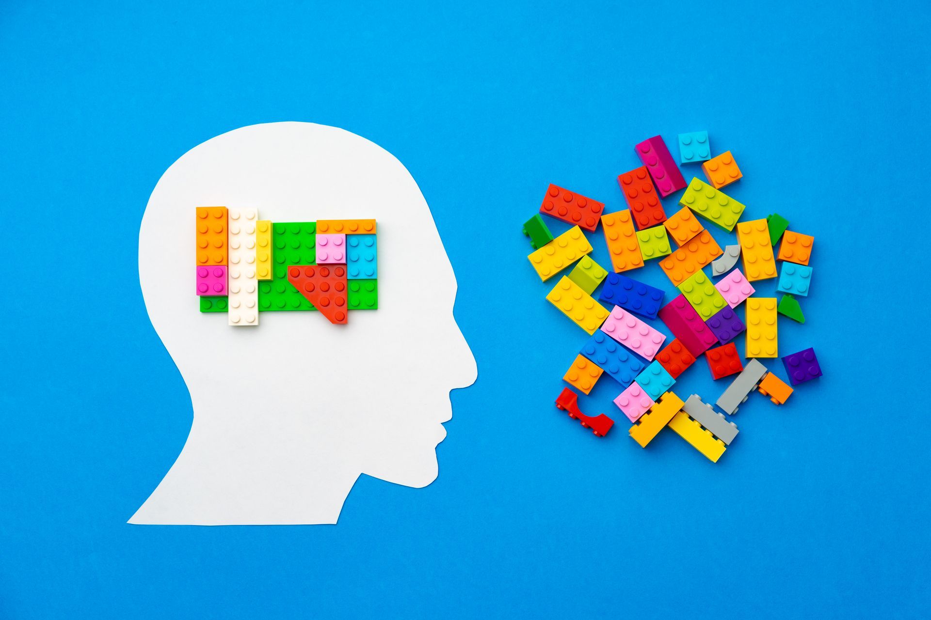 uma cabeça feita de blocos de lego e uma pilha de blocos de lego sobre um fundo azul.