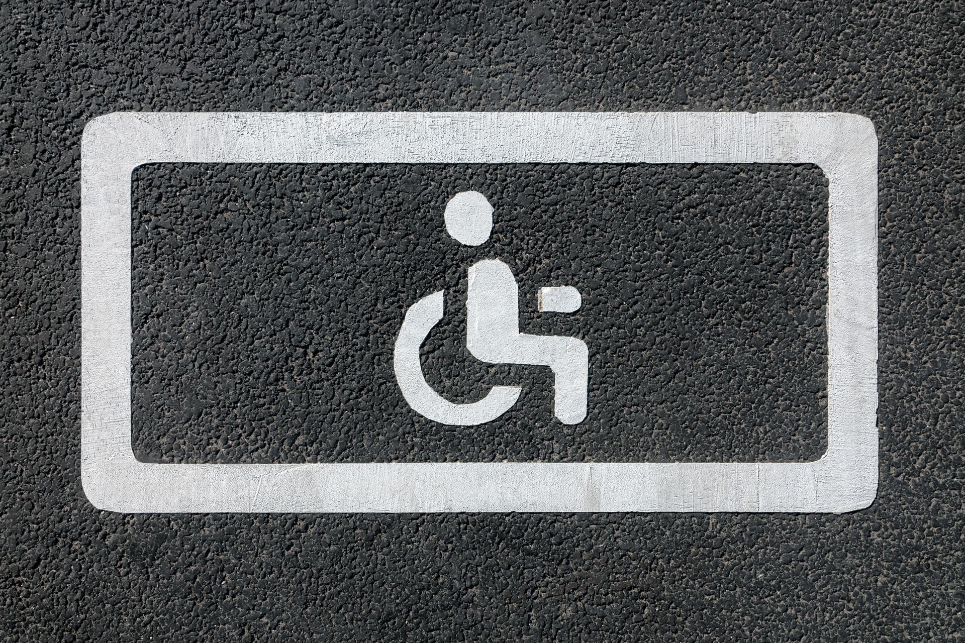 Um sinal de estacionamento para deficientes está pintado no asfalto em um estacionamento.