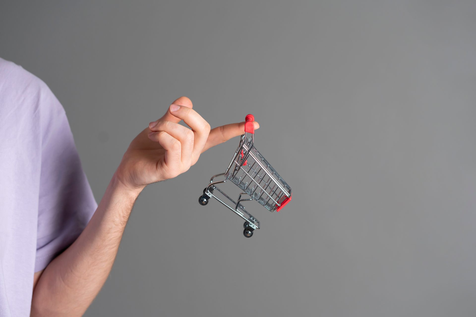 a person is holding a small shopping cart with their finger .