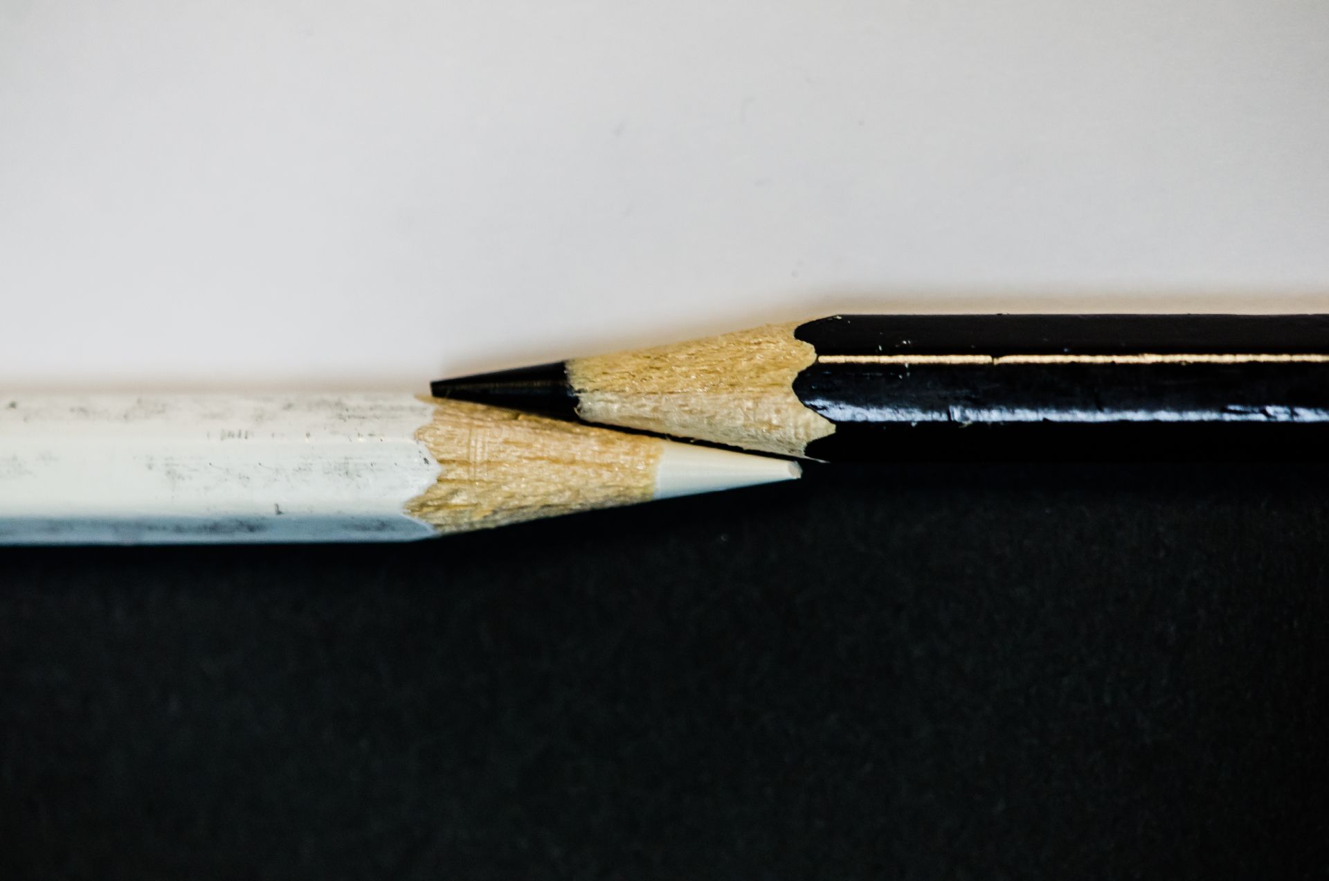 Dois lápis pretos e brancos estão sentados um ao lado do outro em uma superfície preta.