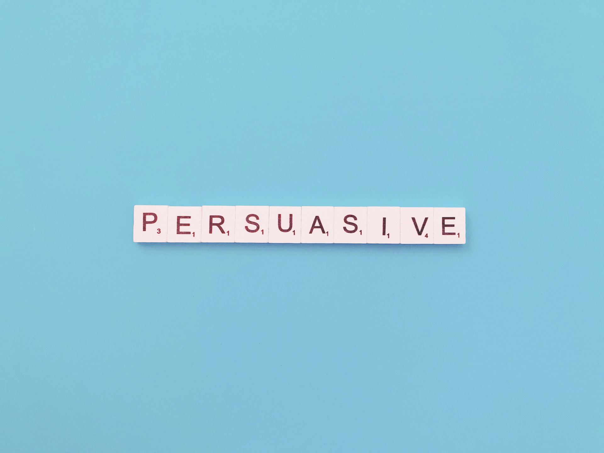 a palavra persuasivo está escrita em blocos de scrabble sobre um fundo azul.