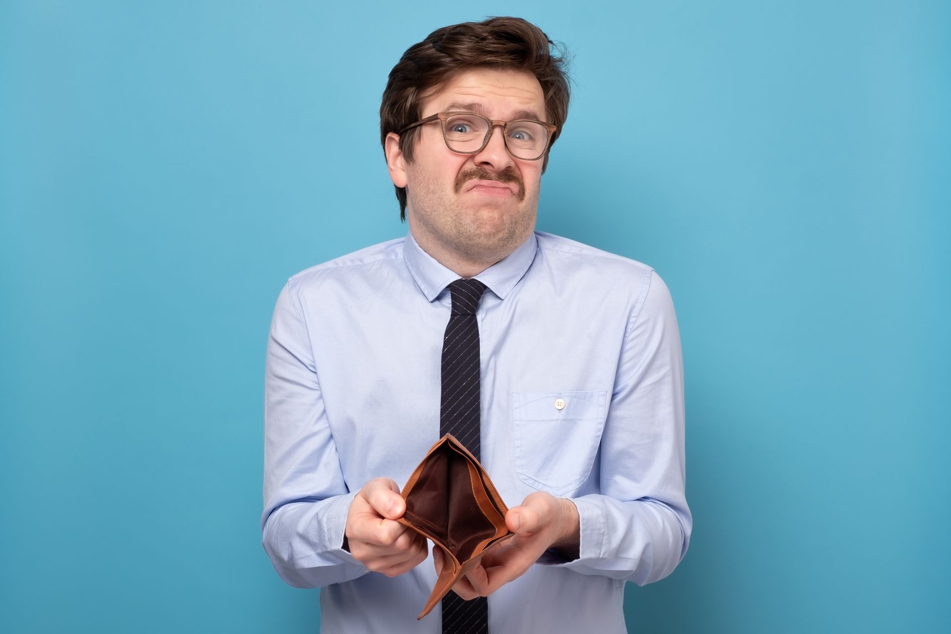 a man in a blue shirt and tie is holding an empty wallet .