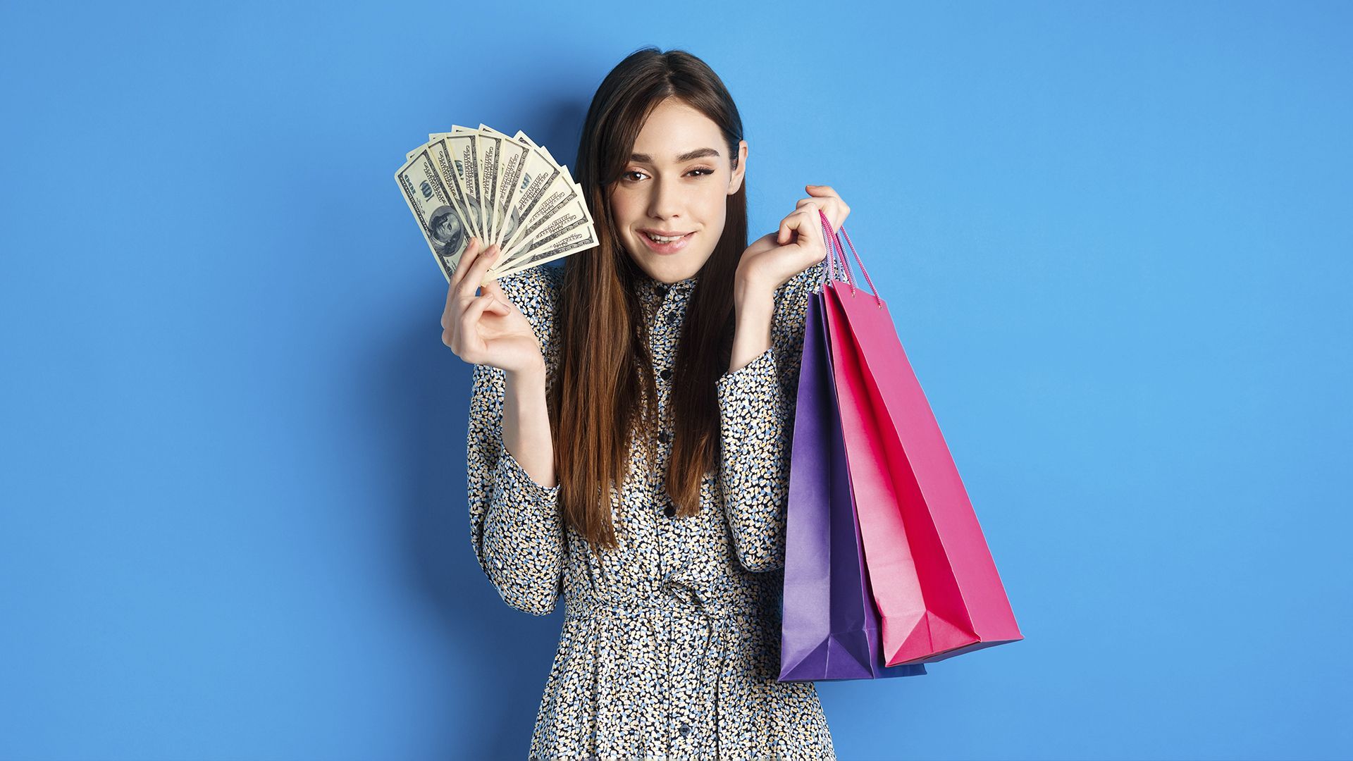 uma mulher está segurando um leque de dinheiro e sacolas de compras.