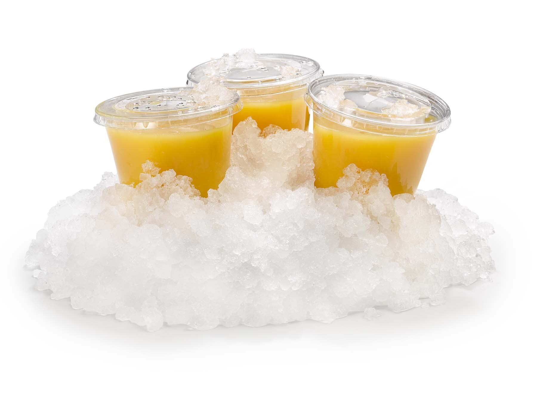 Three cups of orange juice are sitting on top of a pile of ice.