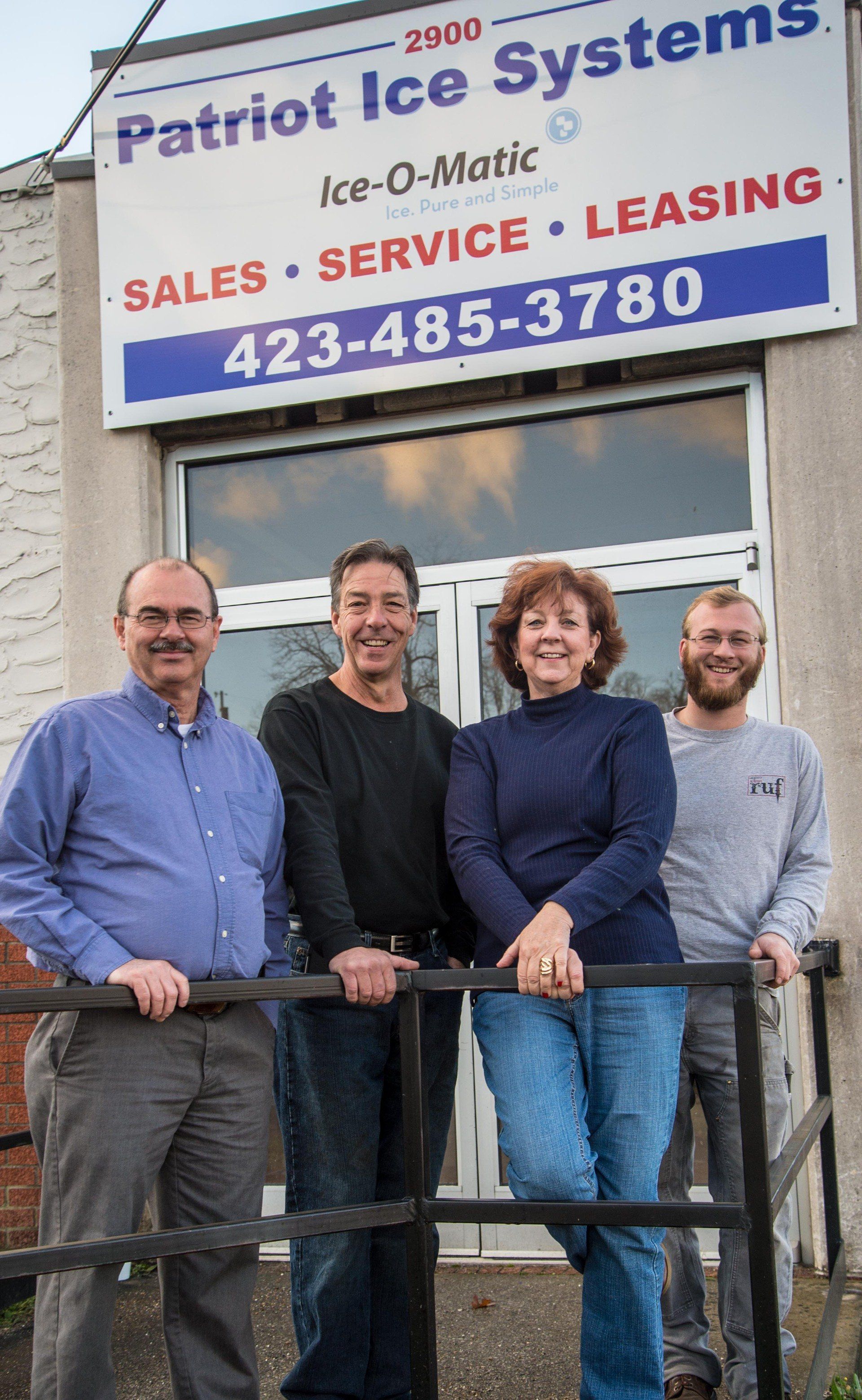 A group of people standing in front of a patriot ice systems sign