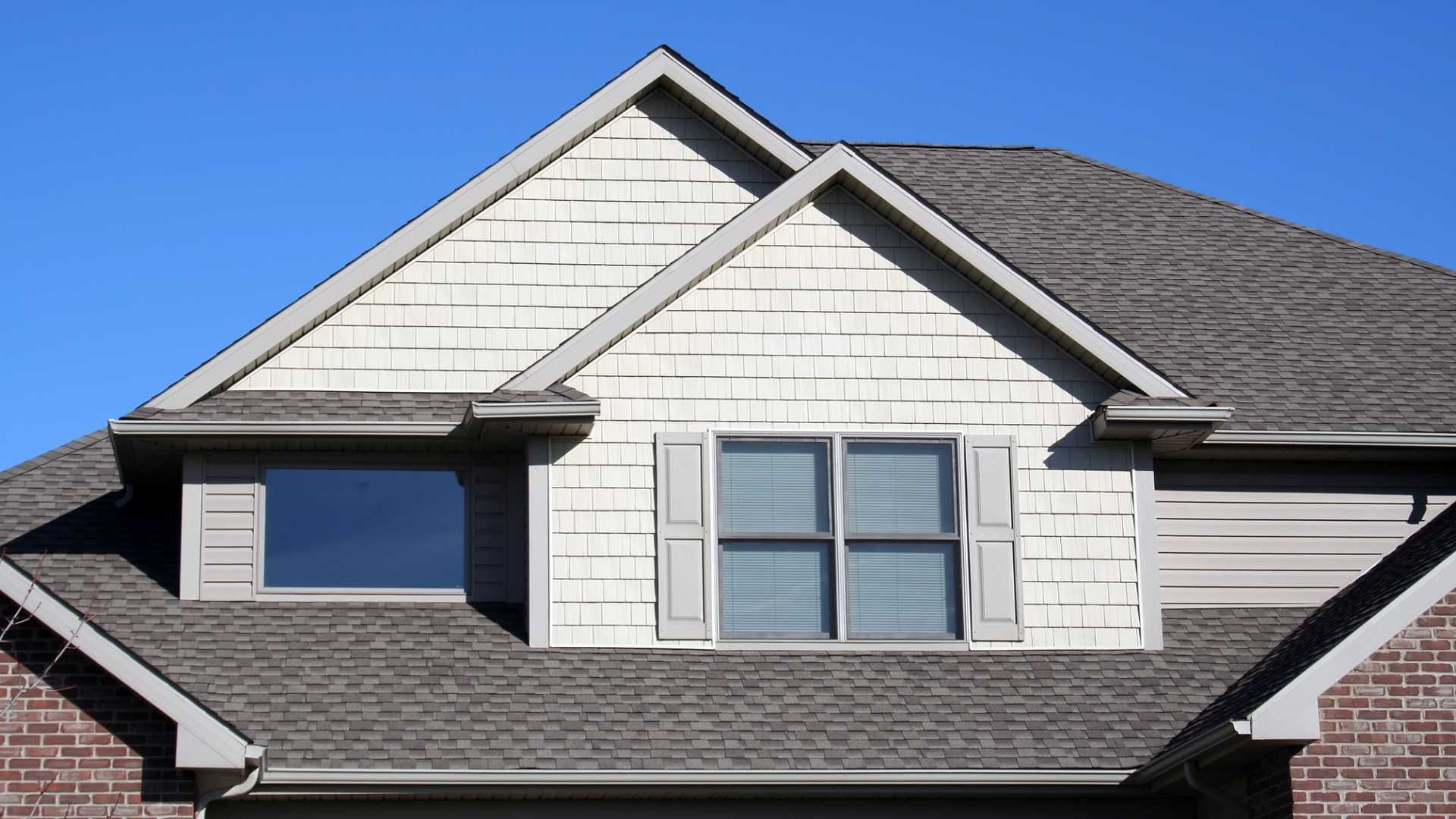 A brick house with a gray roof and white siding