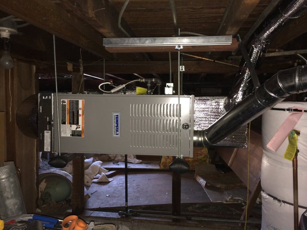 An air conditioner is hanging from the ceiling in a basement.