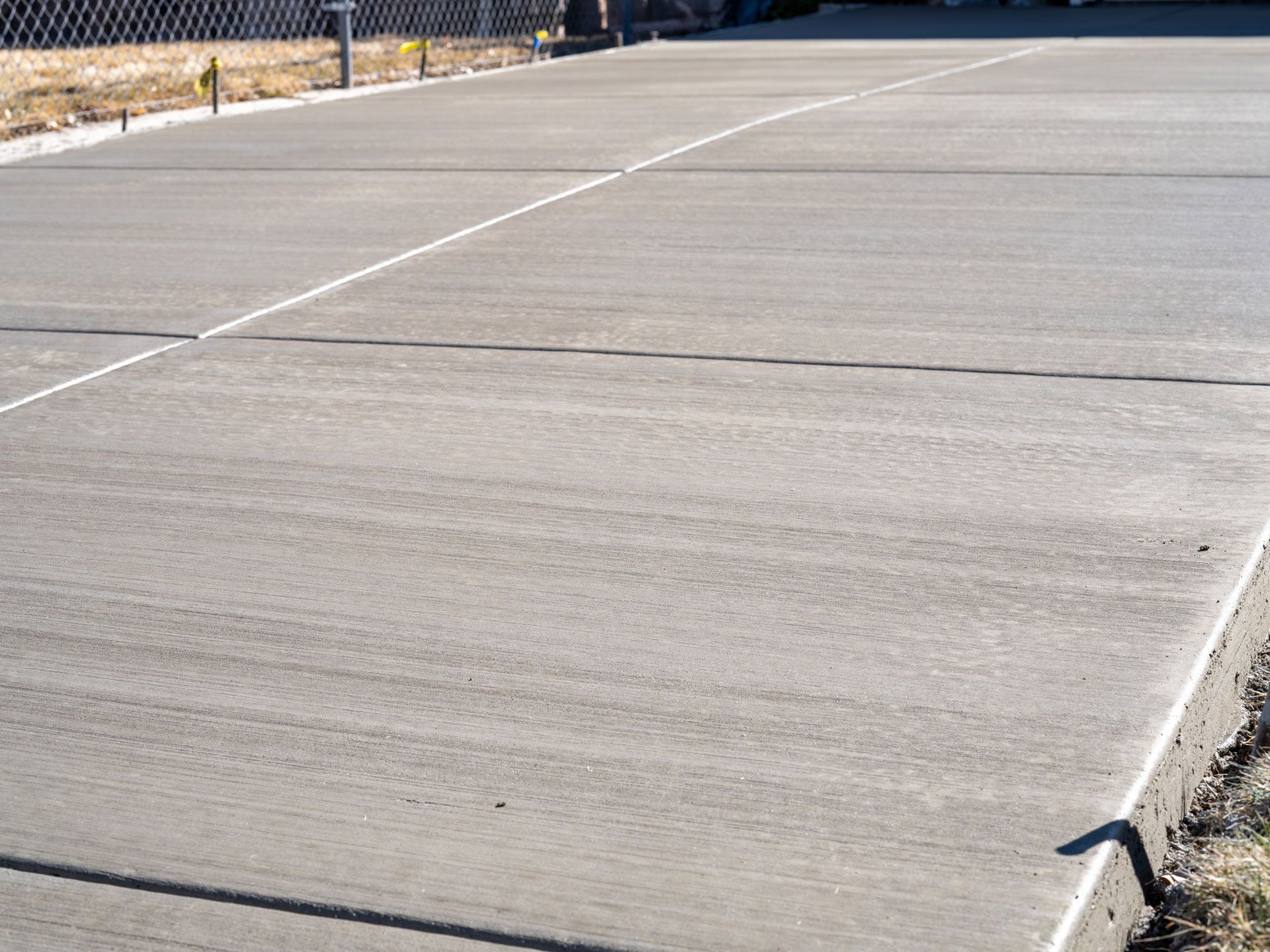 Gray concrete driveway with expansion joints and a slight curve.