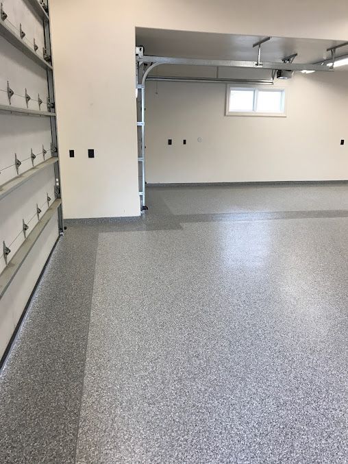 Gray speckled epoxy floor in a garage with a white door frame, white walls, and a small window.