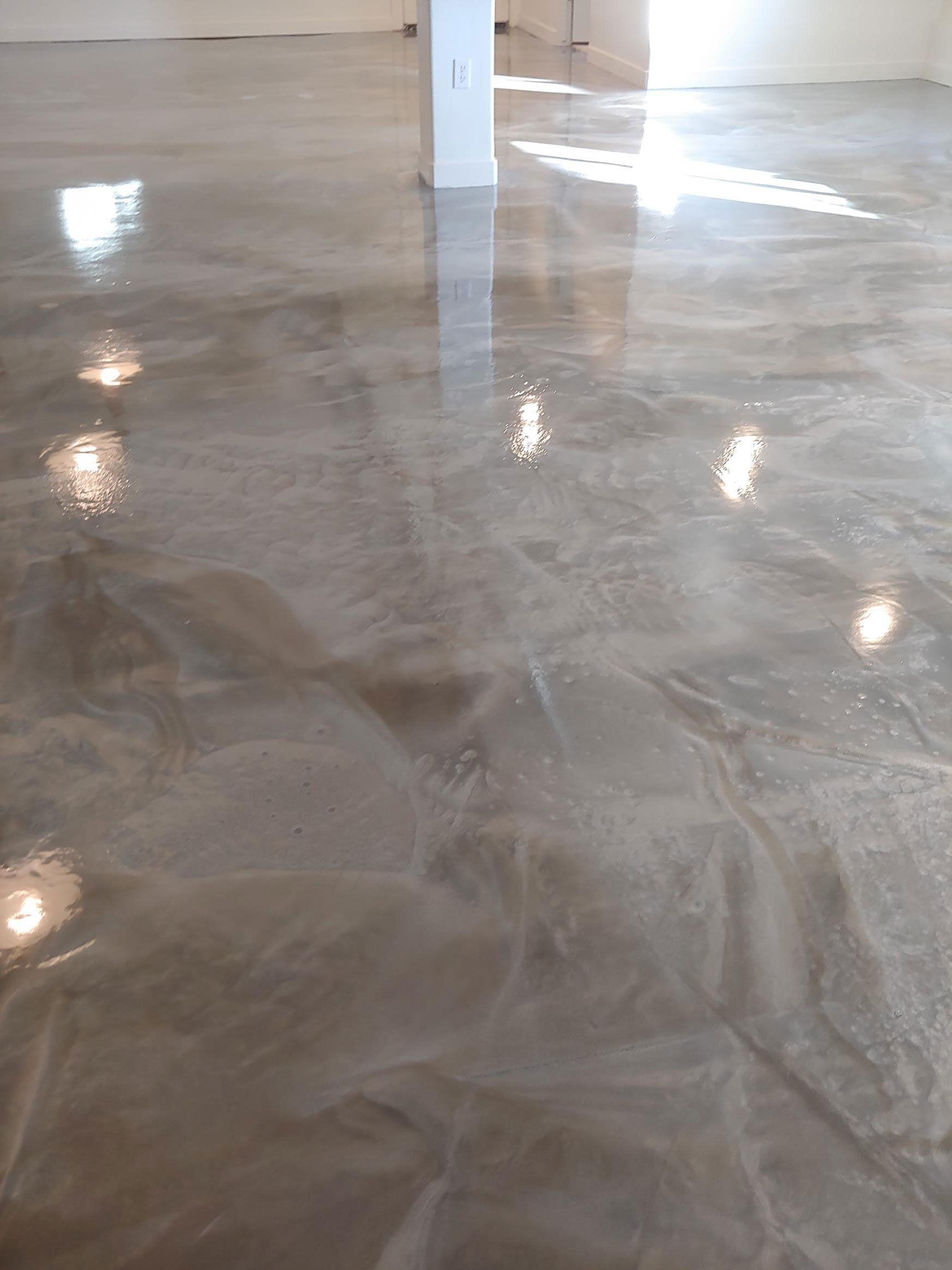 Shiny, metallic-looking concrete floor with reflective light patterns in a room.