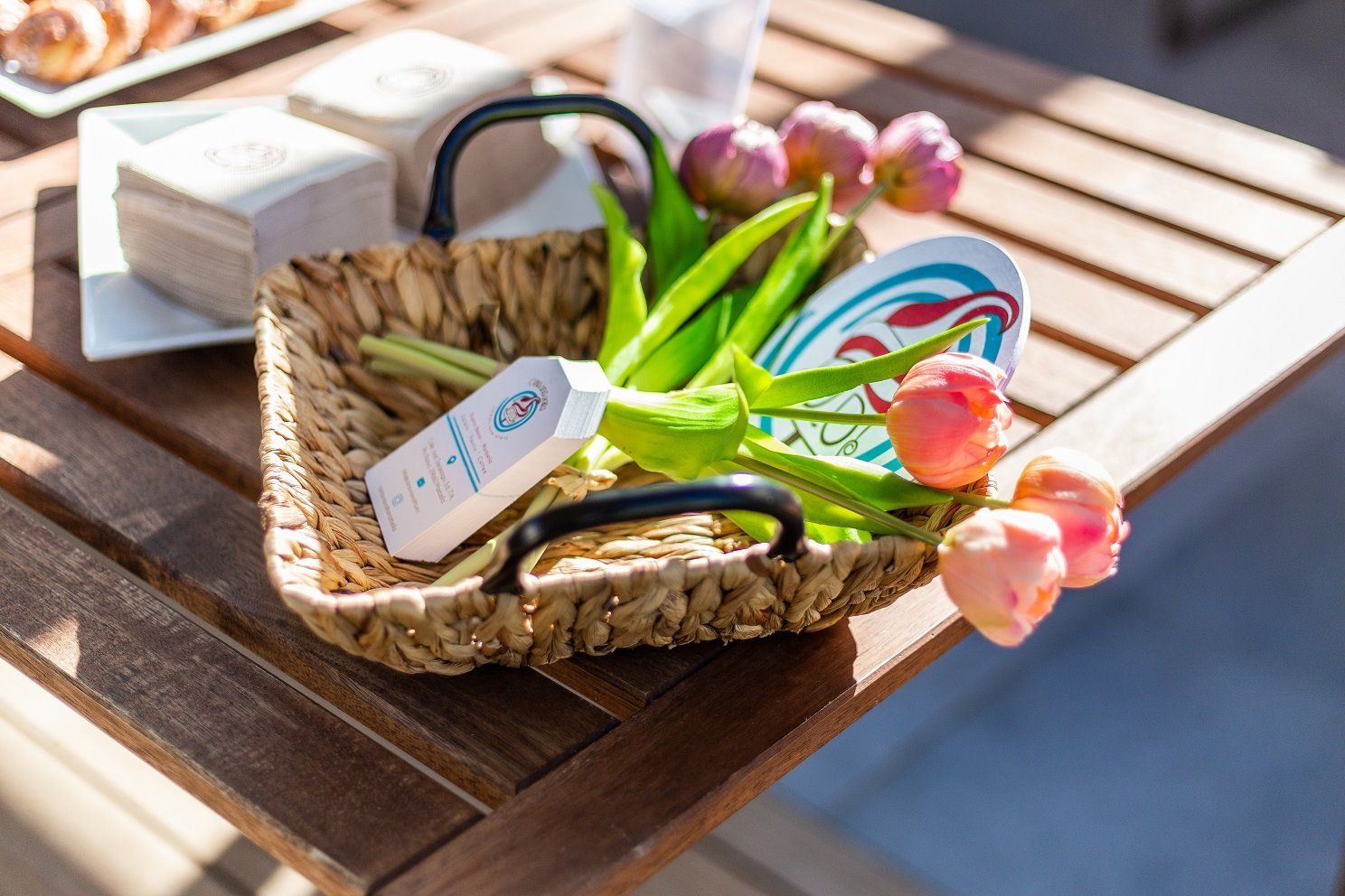 Wicker basket with tulips and other items on a wooden table.