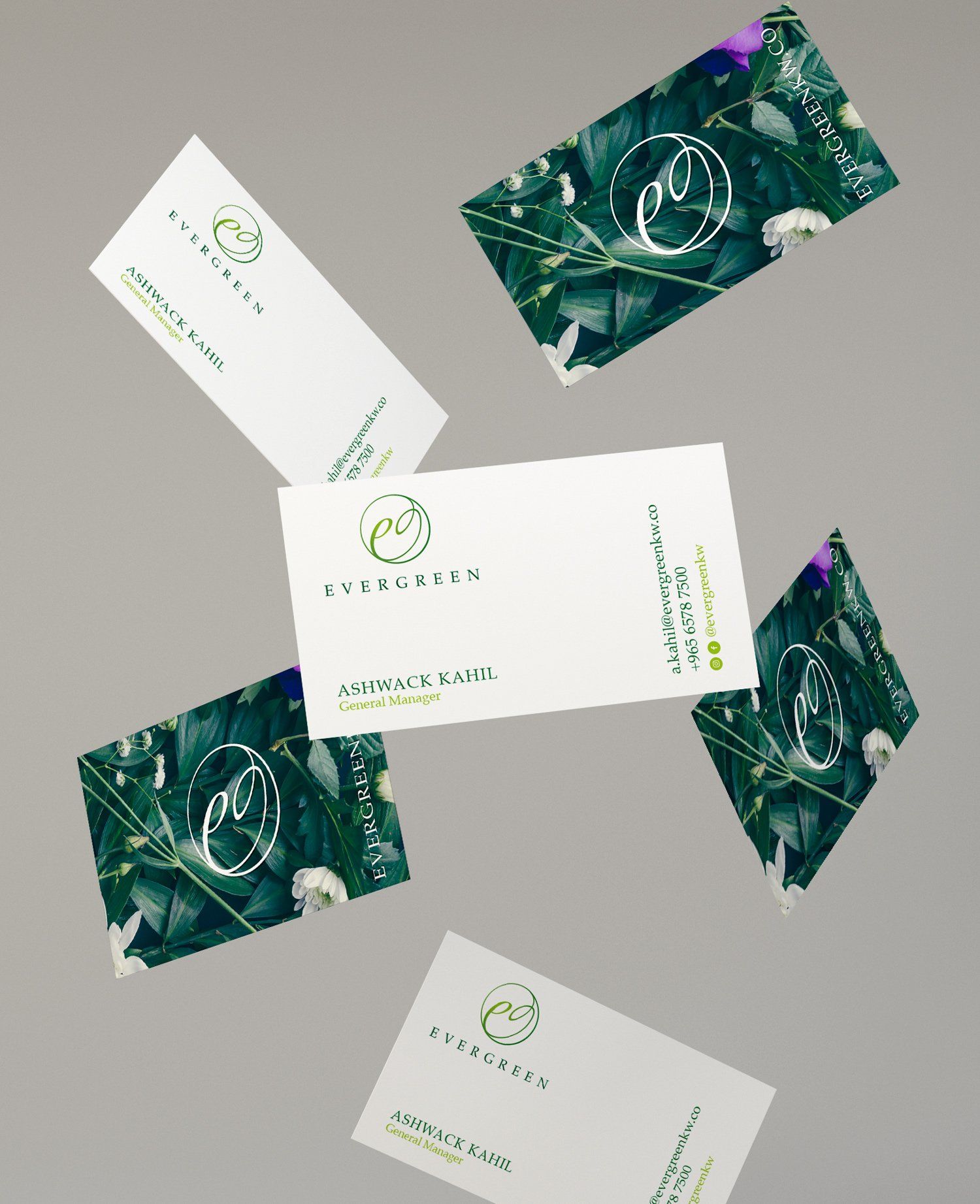 Business cards with green floral background and white logo floating on a gray background.