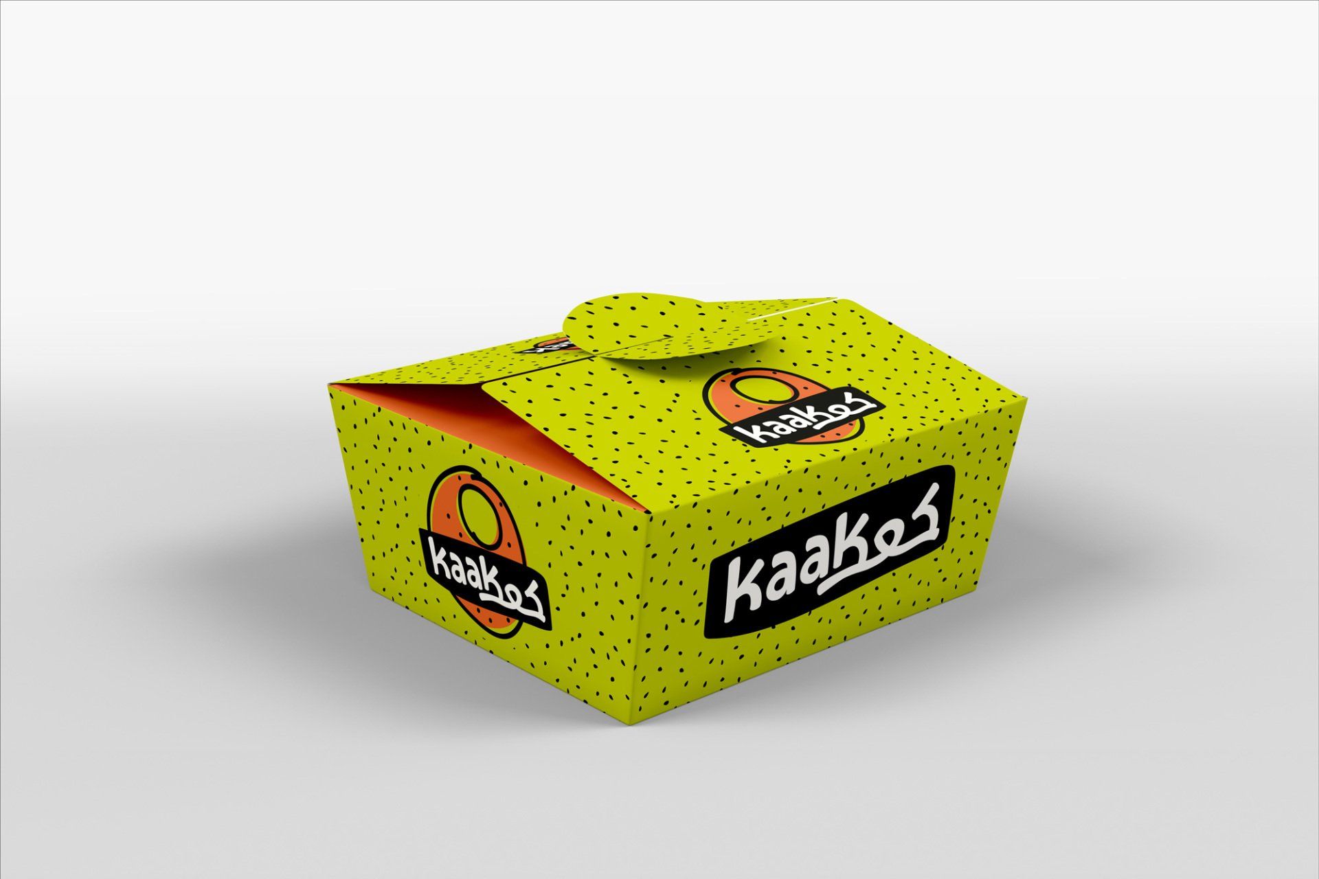 Green Kaakos food box with black lettering and logo, dotted texture, orange interior, on a white surface.