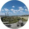 Picnic tables overlook a landscape with a blue sky and scattered clouds.