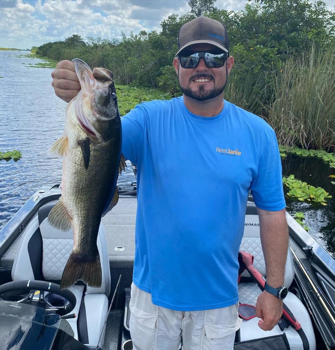 A man in a blue shirt is holding a large fish on a boat.