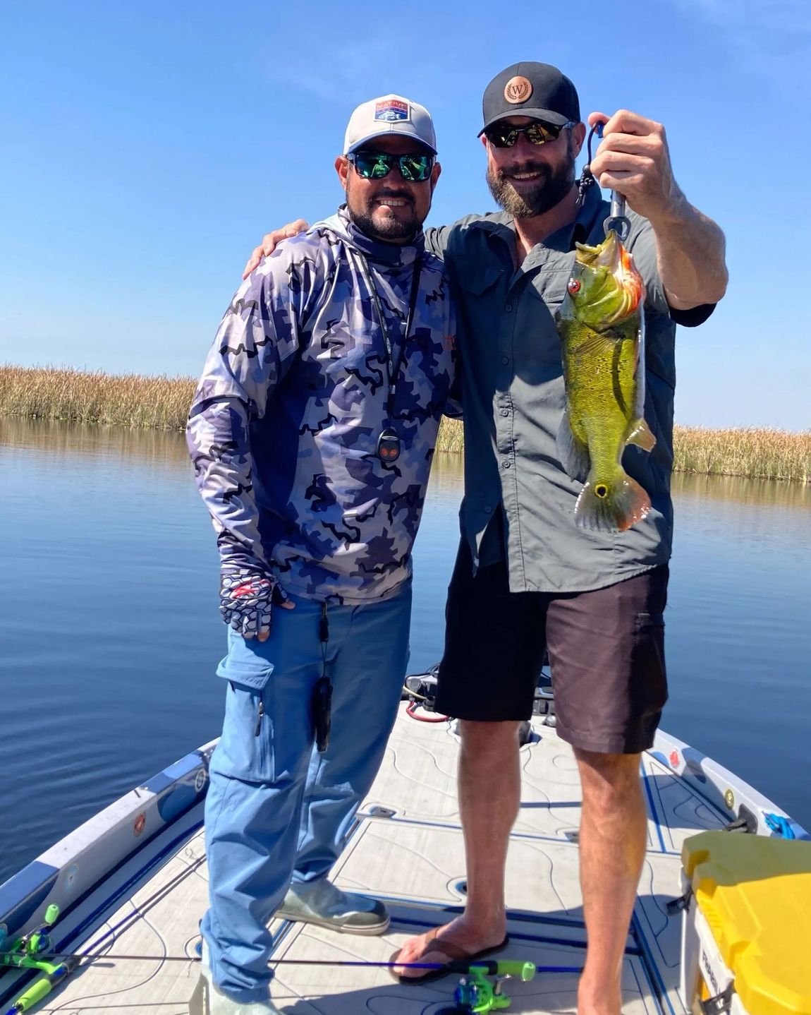 Two men are standing on a boat holding a fish.