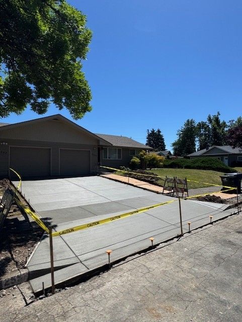 A freshly poured concrete driveway leading to a garage under a clear blue sky.