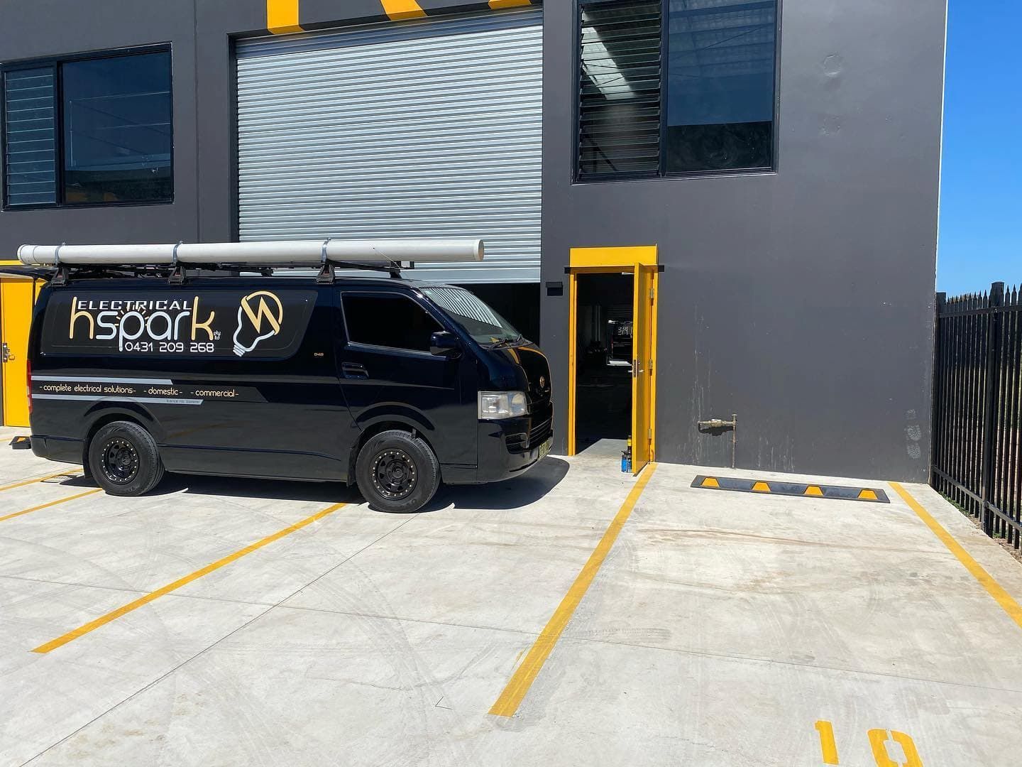 Black Van Parked Near a Grey Building With Open Yellow Door — Hspark Electrical PTY LTD in Austinmer, NSW