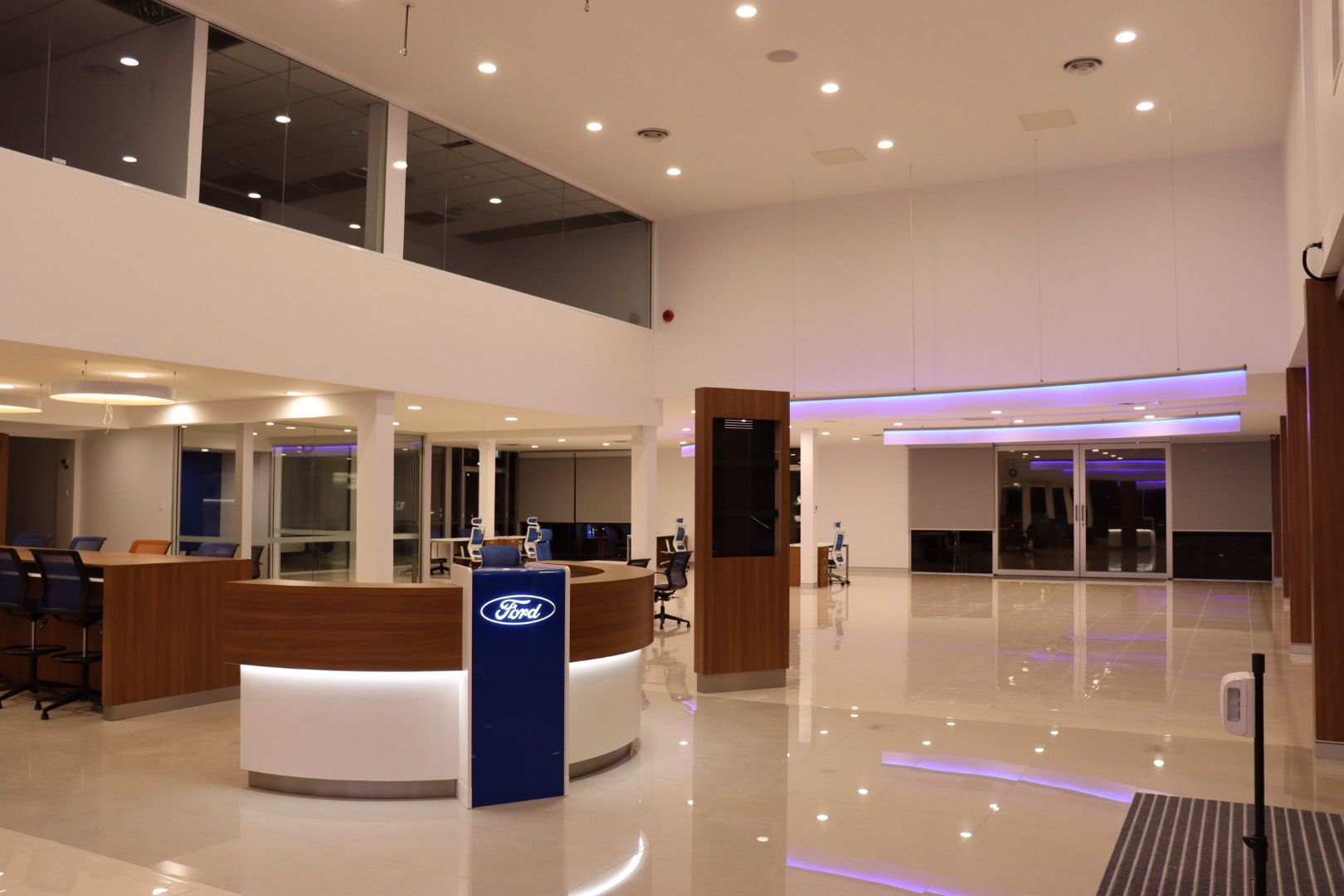 A modern, well-lit Ford dealership interior with a white curved reception desk featuring the Ford logo — Hspark Electrical PTY LTD in Wilton, NSW