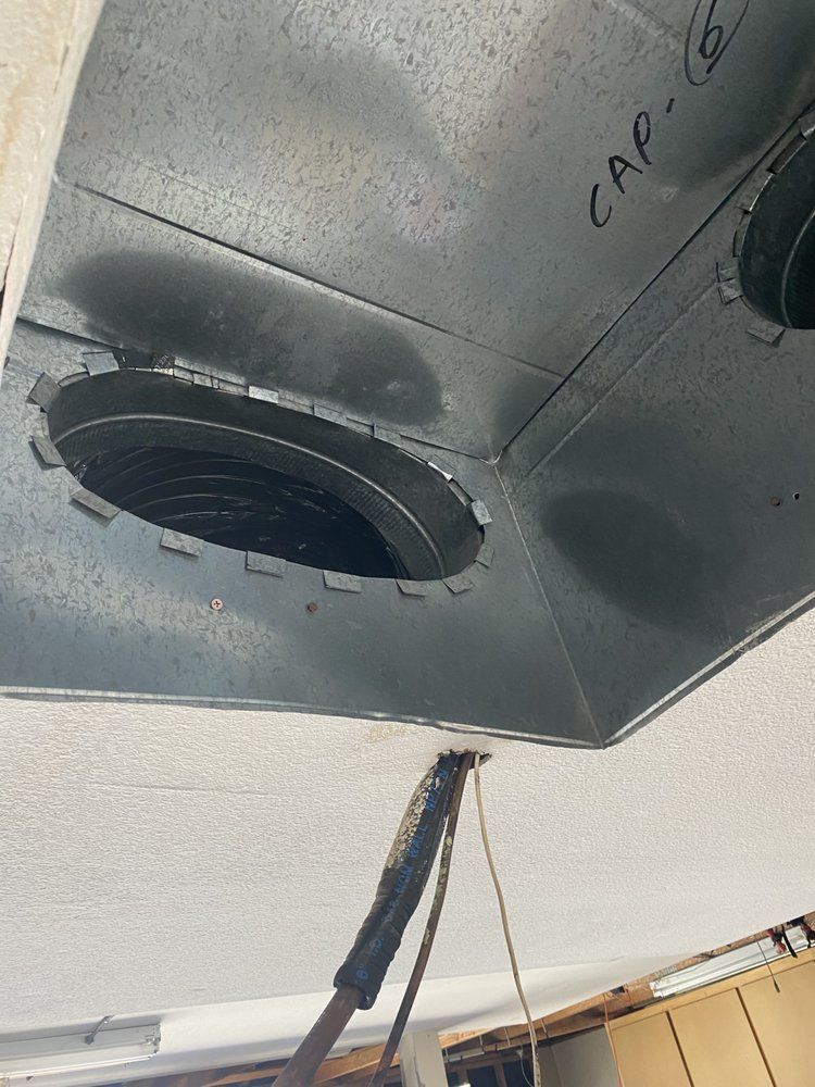 Inside view of a metallic duct with two circular openings, one labeled 